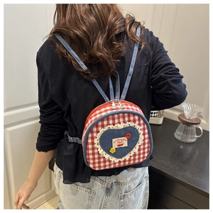 Detail of red checkered mini backpack with denim heart patch and white lace edges