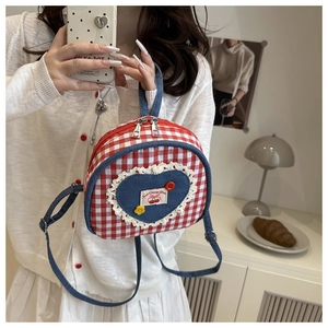 Detail of red checkered mini backpack with blue denim heart patch and lace trim