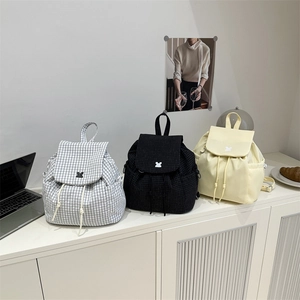 Three minimalist plaid and yellow school backpacks displayed on a modern office desk