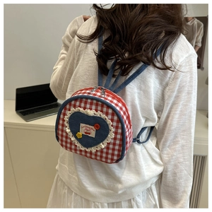 Close-up of red gingham mini backpack featuring a lace heart patch and sweet cherry label