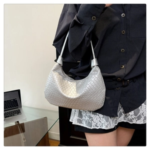 Detail of silver woven shoulder bag showing glossy metallic texture and hobo silhouette