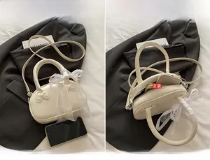 Makroansicht der weißen Muschelhandtasche mit Schleifendesign und Spitzenbesatz