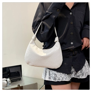 Detail of white woven crescent shoulder bag showing fine texture on a model