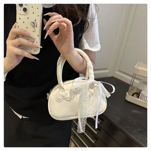 Detail of cream white pillow bag with lace ribbon handle and double bow accents