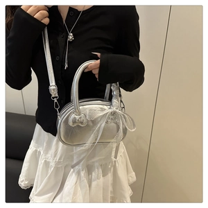 Macro detail of silver metallic mini bag featuring embossed bow and white lace ribbon deco