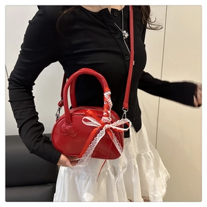 Red patent leather mini bag with white lace bow and heart detail shown on a model