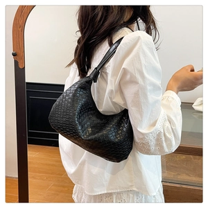 Detailed view of black woven faux leather hobo bag texture and seamless shoulder strap