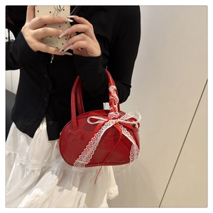 Close-up of red patent leather shell bag with embossed cat face and lace bow detail