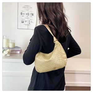 Close-up of golden metallic woven hobo bag with a stylish knot detail on shoulder strap