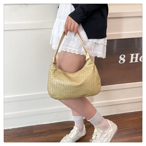 Detail of golden woven hobo bag showing fine texture and metallic finish on shoulder