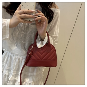 Detail of burgundy V-quilted faux leather crossbody bag with elegant gold-tone hardware