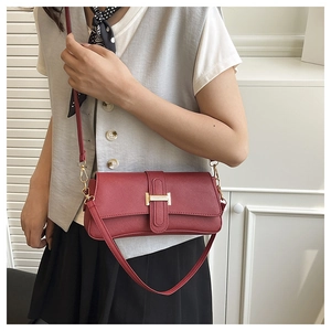 Close-up of burgundy leather crossbody bag featuring a golden H-shaped buckle detail