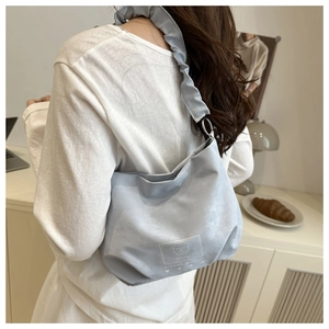 Detail of light blue pleated shoulder bag with Altumi branding on white top