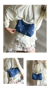Close-up of floral embroidery on navy blue denim tote bag with silver knotted straps