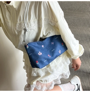 Detail of denim tote bag with pink floral embroidery and silver knot shoulder strap