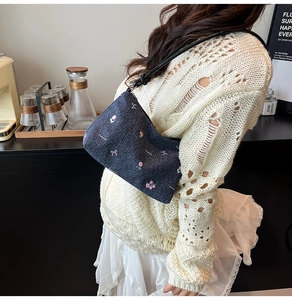Detail of denim shoulder bag with floral embroidery and bow accents on model