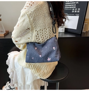 Close-up of denim shoulder bag featuring pink floral embroidery and bow patterns