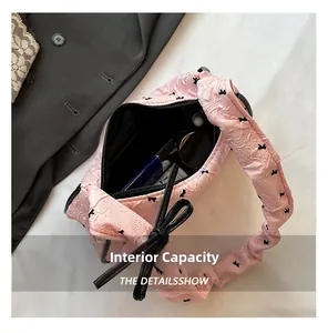 Internal view of the pink bow shoulder bag showing storage for sunglasses and makeup