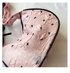 Detail of pink pleated texture fabric with black bow embroidery and leather piping