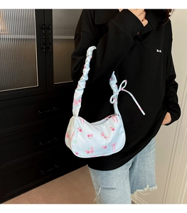 Detail of light blue nylon bag featuring pink rose patterns and pleated handle style
