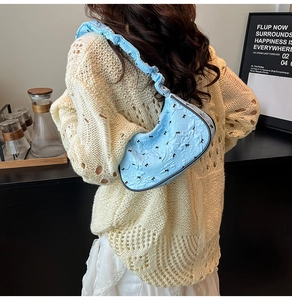 Detail of light blue pleated shoulder bag with black bows and scrunchie strap