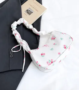 Close-up of floral nylon shoulder bag with ruffled strap and pink rose patterns