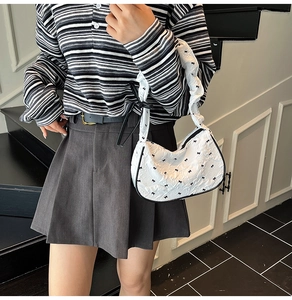 Detail of white puff shoulder bag with black bow embroidery and ruched cloud handle