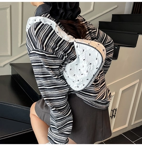 Detail of white quilted half-moon bag featuring black bows and ruffled shoulder strap