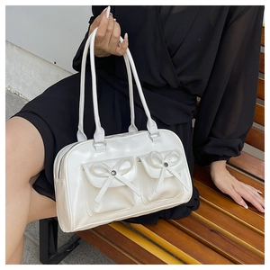 Detail shot of white PU leather bag featuring front pockets with large bow decorations