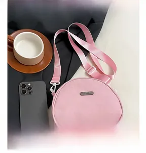 Pink nylon mini crescent bag shown with a smartphone and coffee cup for scale