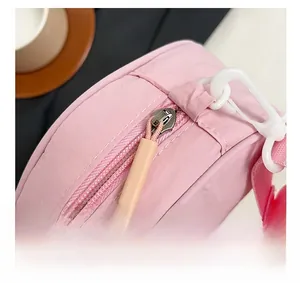Detailed close-up of pink nylon crossbody bag with durable zipper and white buckle detail