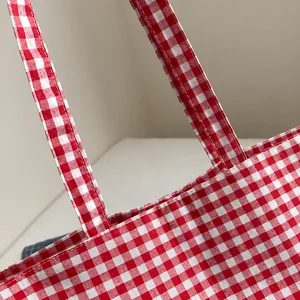 Close-up of durable red and white gingham canvas fabric and stitching details on the tote bag