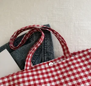 Detail of red and white gingham canvas tote bag showing silver magnetic snap closure and strap