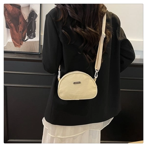 Close-up of beige nylon crescent bag featuring a metallic logo and thick shoulder strap