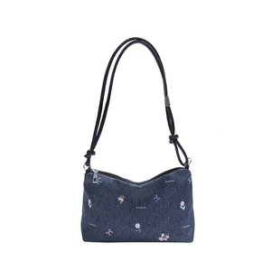 Blue denim tote bag with pink floral embroidery and black rope shoulder strap on white base