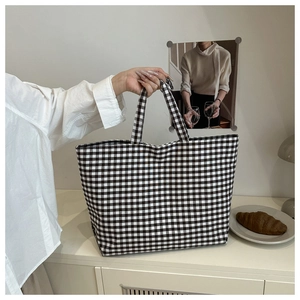 Detail of large checkered canvas tote bag with wide handles for daily casual use