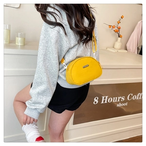 Detail of a bright yellow nylon shell crossbody bag with adjustable white strap buckle