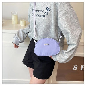 Detail of purple crescent nylon crossbody bag with an adjustable wide white shoulder strap