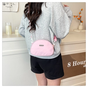 Pink semi-circular nylon crossbody bag with metal logo and shoulder strap on model