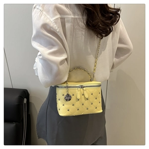 Detail of yellow quilted vanity case with silver studs and black rose charm pendant