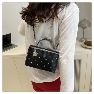 Detail of quilted leather crossbody box bag featuring rhinestone accents and rose charm
