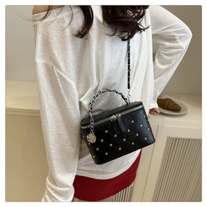 Detail of black quilted leather box bag with silver studs and a rose pendant charm