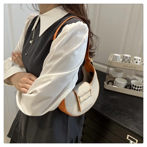 Détail du sac demi-lune en tweed crème avec garniture orange et boucle dorée ondulée