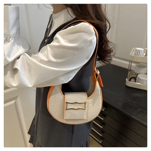 Detail of beige canvas shoulder bag featuring orange leather trim and golden buckle
