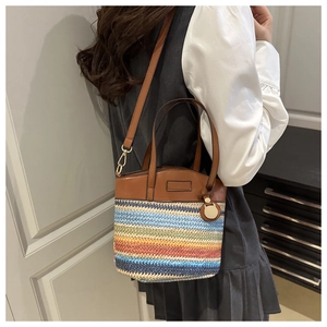 Détail du sac seau en paille tissée à rayures arc-en-ciel avec finitions en cuir marron