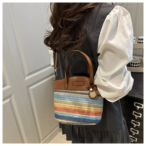 Detail of rainbow woven phone bag with brown leather handles and adjustable strap