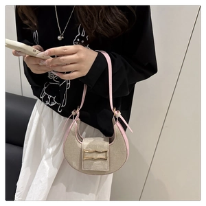Detailed view of beige canvas handbag with pink leather trim and gold metal buckle