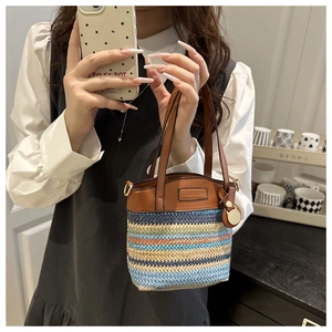 Gros plan d'un sac seau en paille coloré avec des poignées en cuir marron et rayures