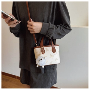 Detailed shot of white mini bucket bag with cartoon prints and brown contrast handles