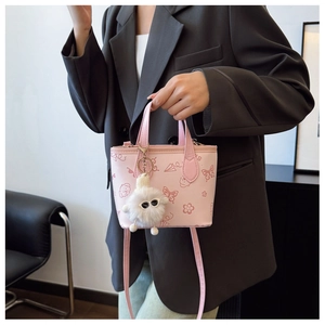 Detailed view of pink tote bag with cartoon patterns and white faux fur charm accessory